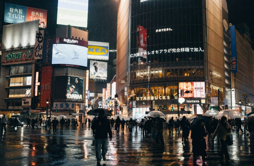 Cityscape at night, full of lights and people.