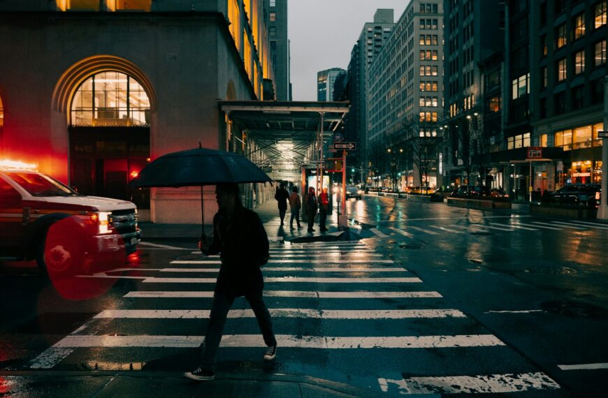 A person crosses a wet street in the city.