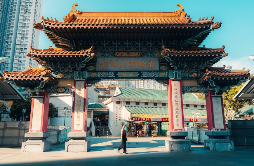 Ornate traditional chinese temple gate with modern buildings behind